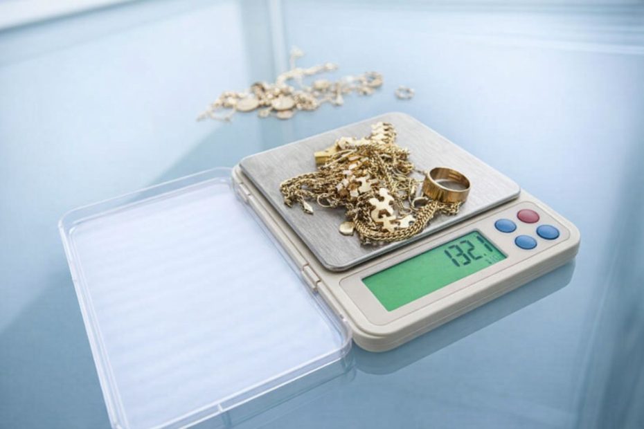 Guldsmycken som vägs på en digital våg för värdering.